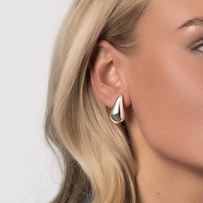 "Elegant dråbeformede øreringe i sølv og guld, skinnende overflade, moderne skulpturelt design til kvinder"