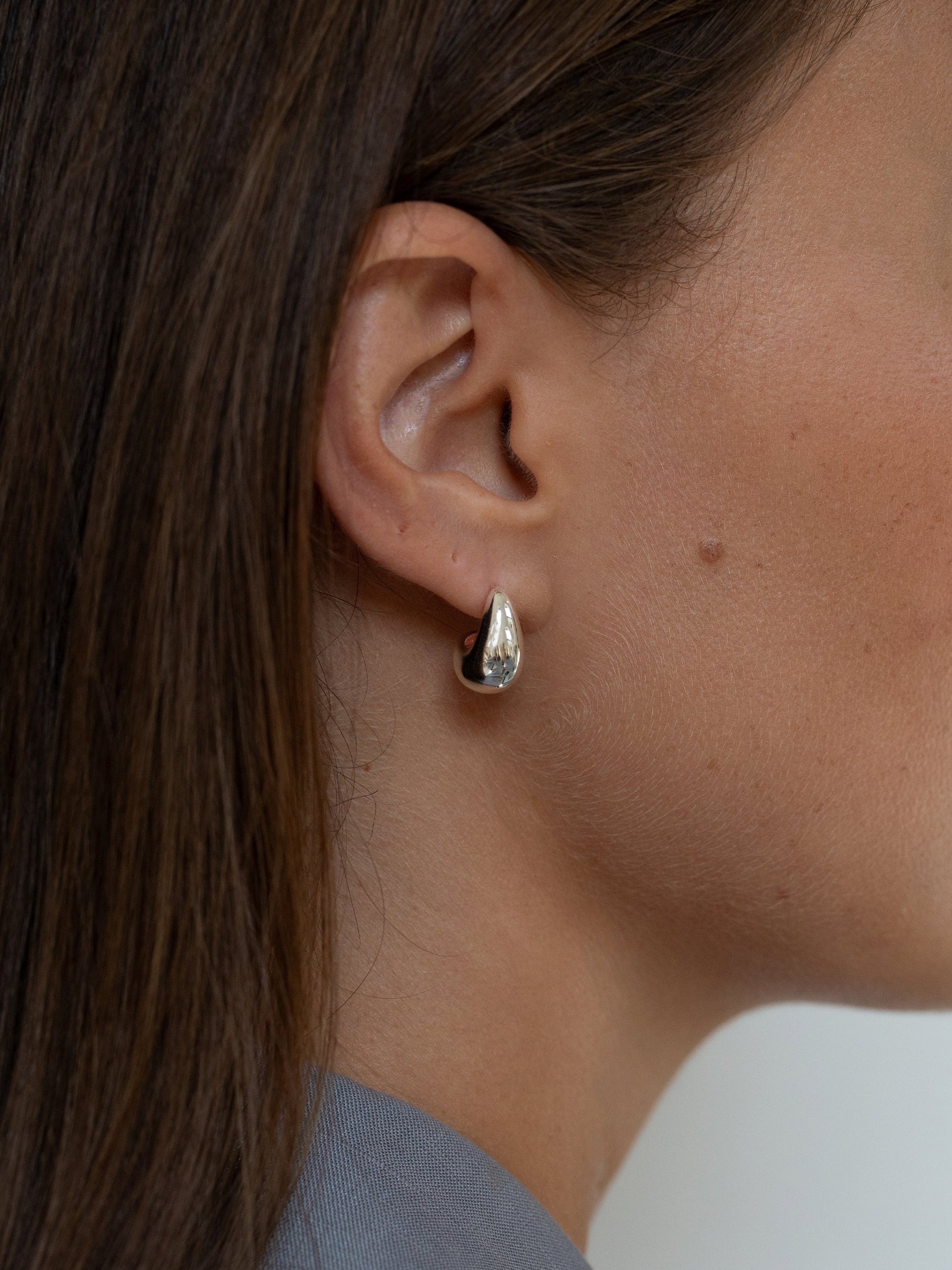 "Elegant dråbeformede øreringe i sølv og guld, skinnende overflade, moderne skulpturelt design til kvinder"