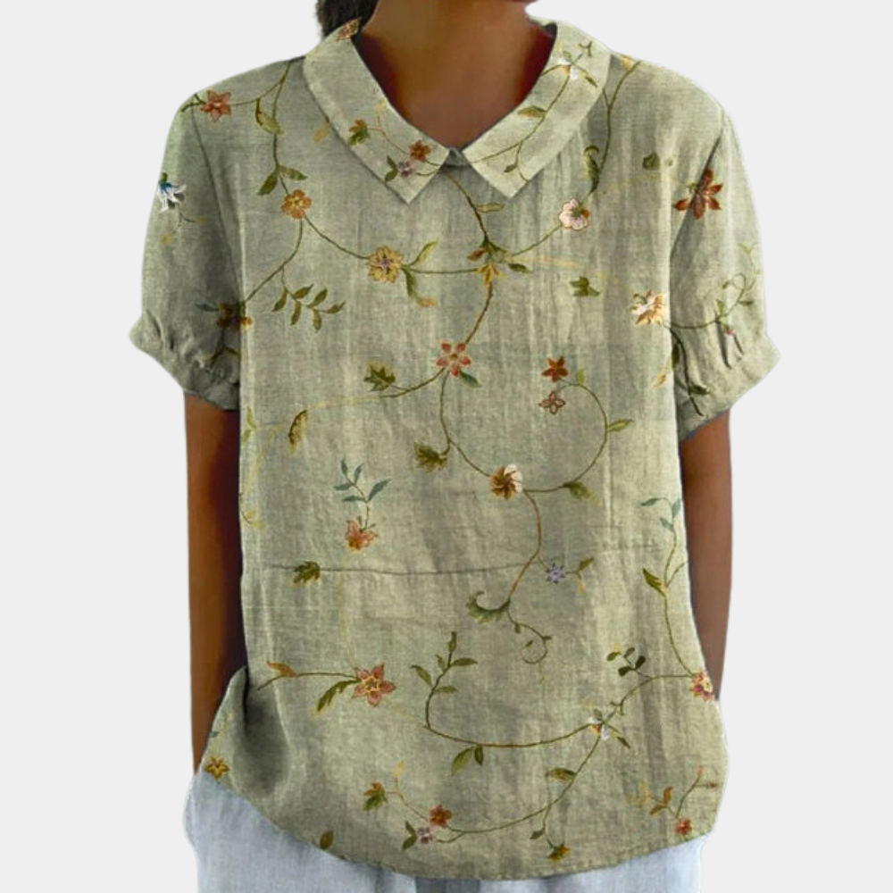 "Farverig damebluse med blomstermønster, rund krave og sommerstil. Perfekt til garderobeopgradering."