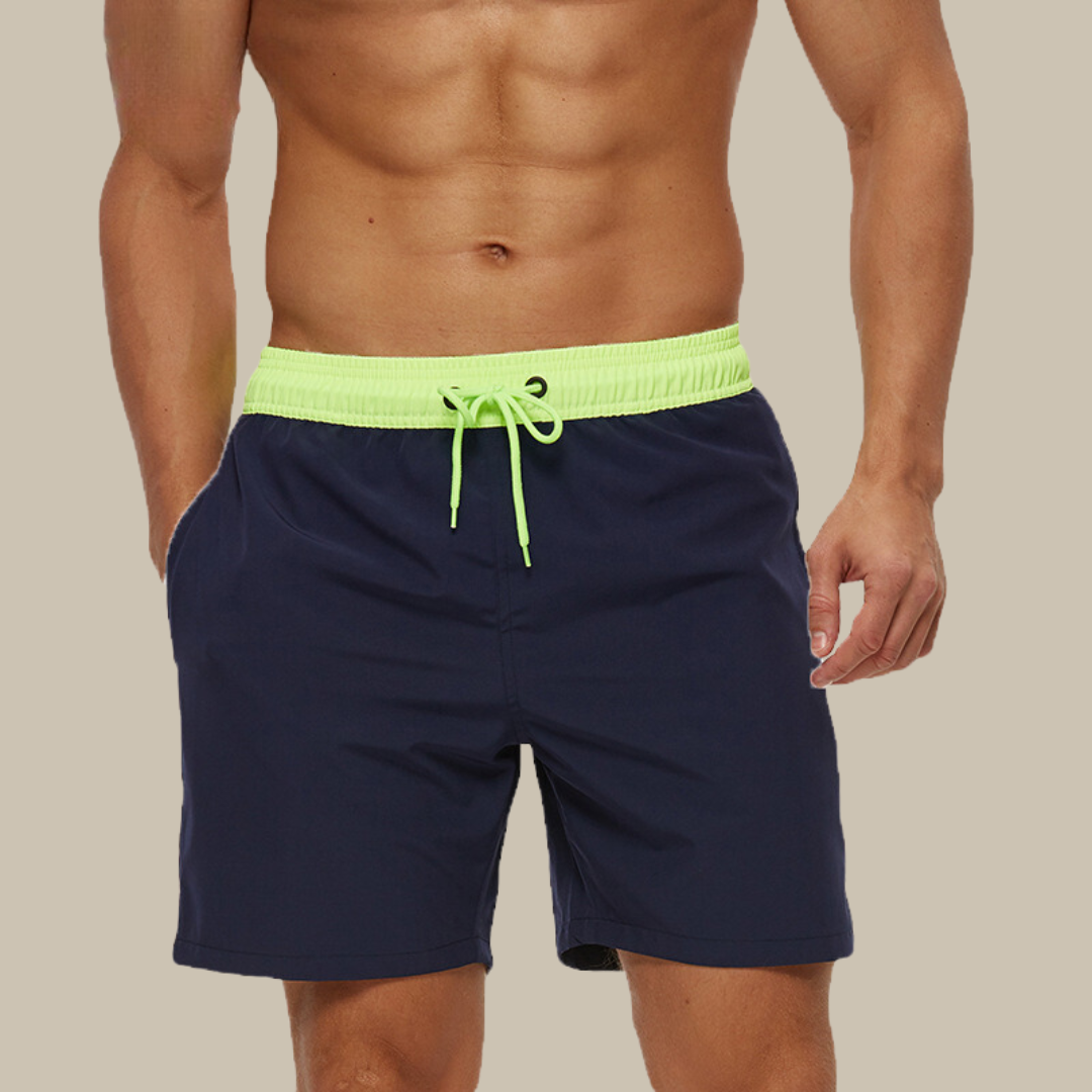 "Hurtigtørrende herrebadeshorts med lynlåslommer og elastisk pasform, set forfra, i blå polyesterstof."