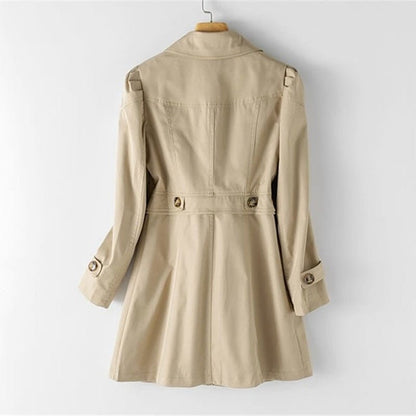 Kvindelig trenchcoat i beige med klassisk snit, knaplukning, letvægts og vandafvisende materiale. Set forfra mod baggrund.