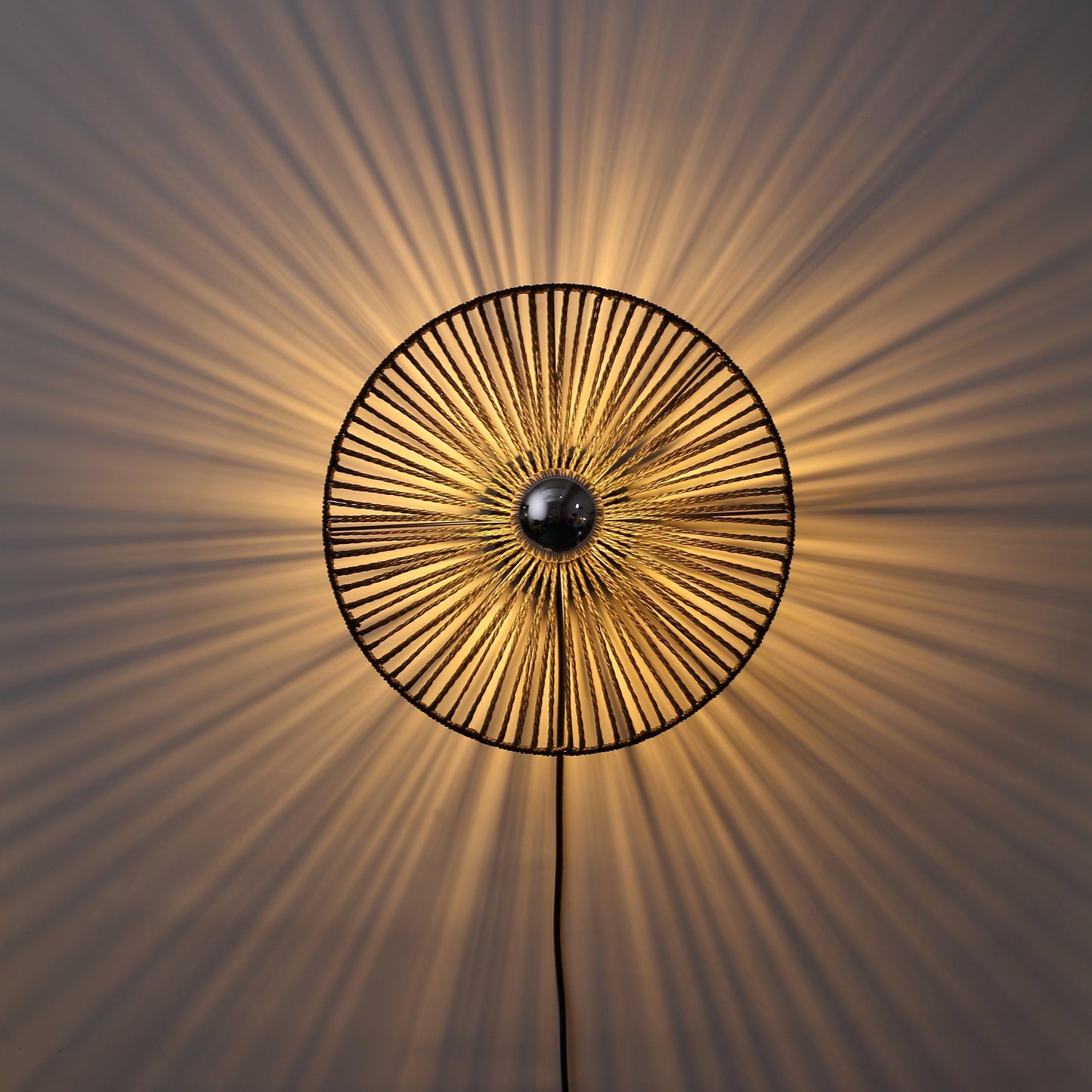 "Sort Ø40 væglampe med rund form skaber stemningsfuldt lys; lavet af flettet papirrebs materiale for et naturligt look."