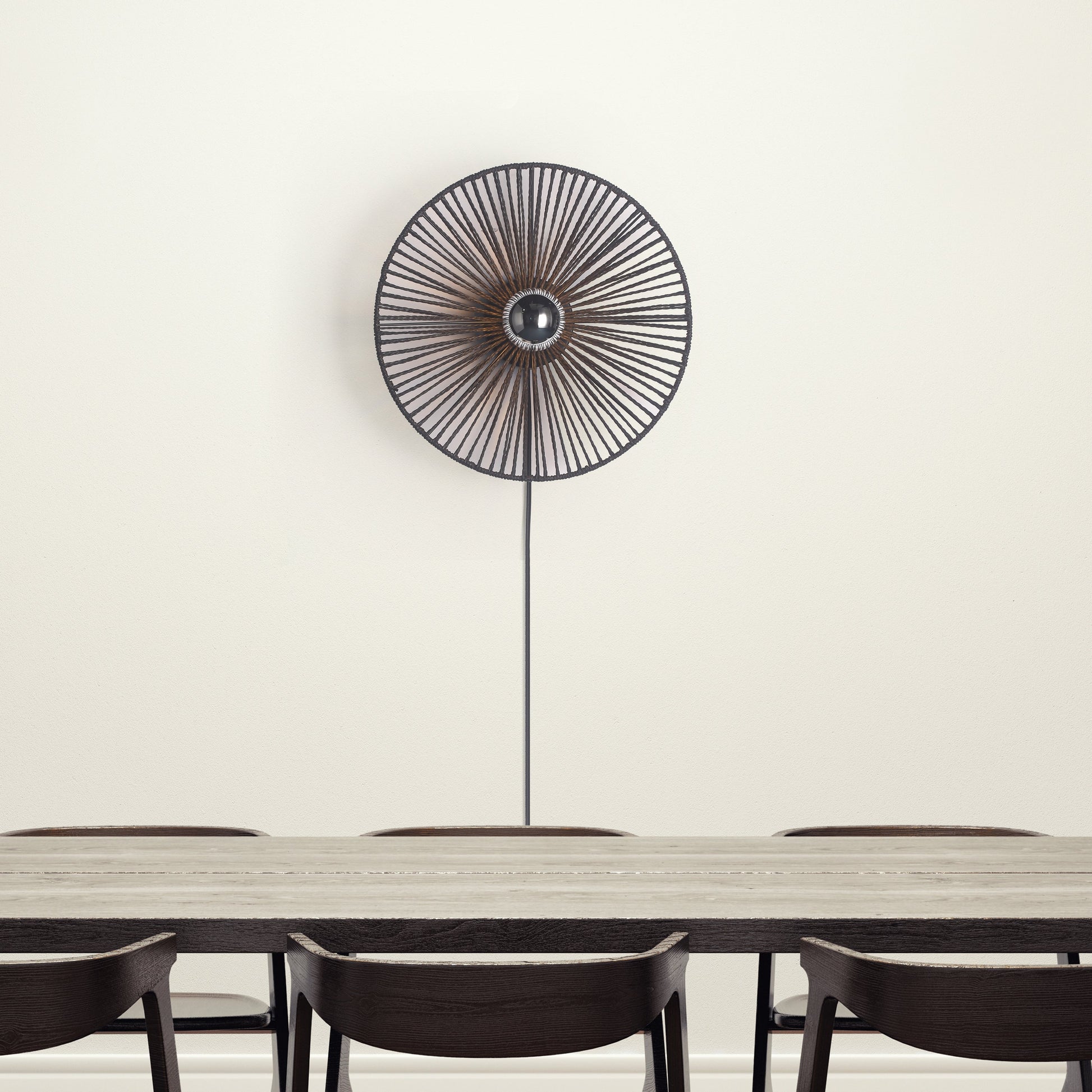 "Sort Ø40 væglampe med rund form skaber stemningsfuldt lys; lavet af flettet papirrebs materiale for et naturligt look."