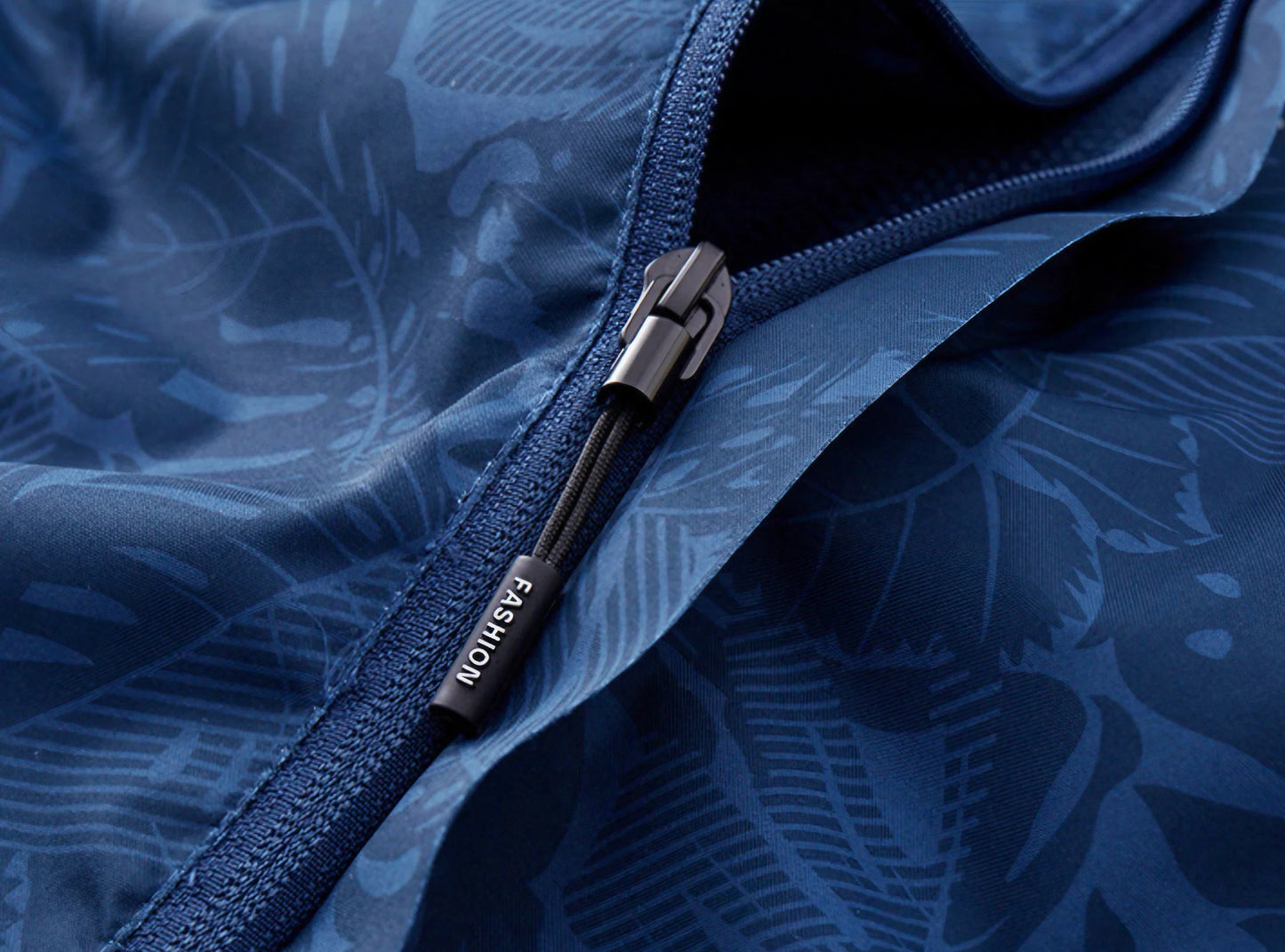 Vind- og vandtæt kvindejakke i åndbart stof med justerbar hætte og smukt bladprint, ideel til alle vejrforhold.