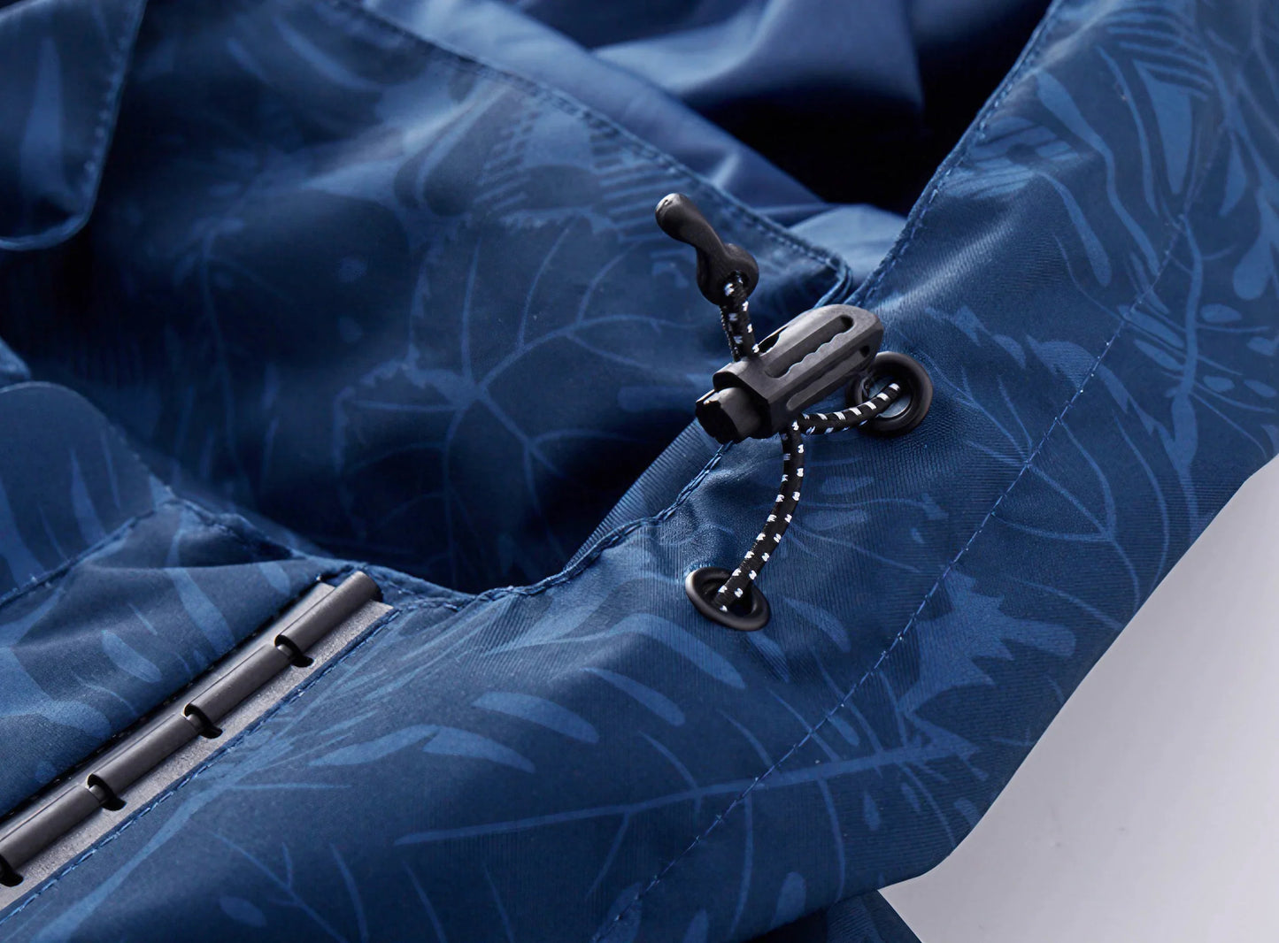 Vind- og vandtæt kvindejakke i åndbart stof med justerbar hætte og smukt bladprint, ideel til alle vejrforhold.