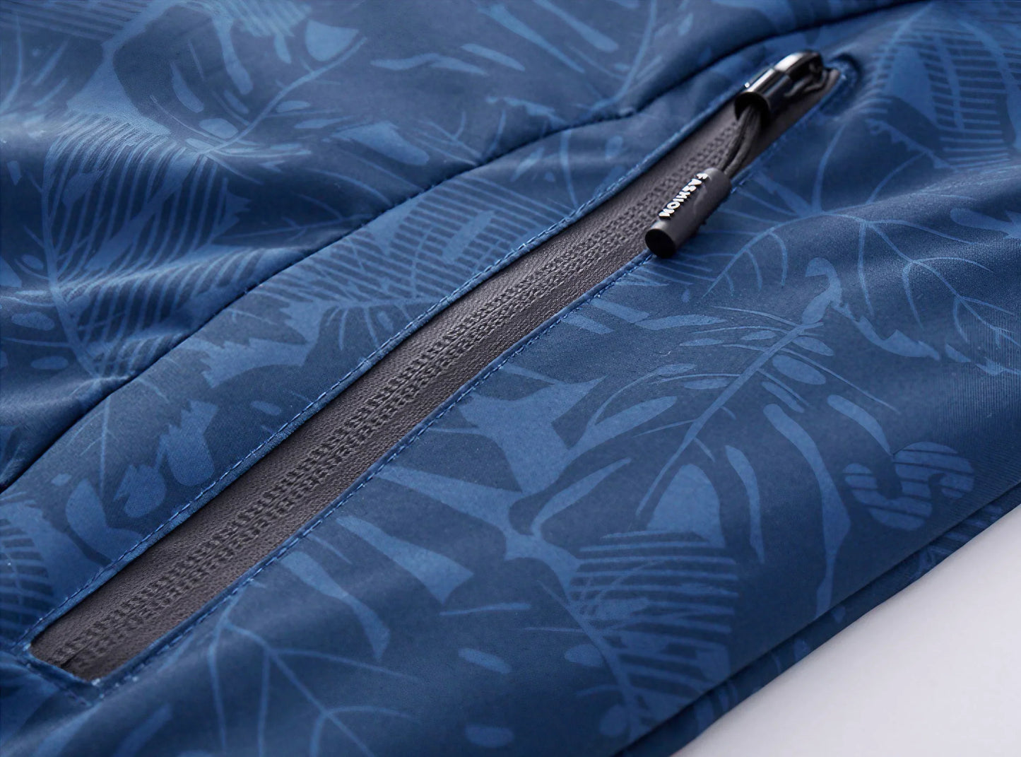 Vind- og vandtæt kvindejakke i åndbart stof med justerbar hætte og smukt bladprint, ideel til alle vejrforhold.